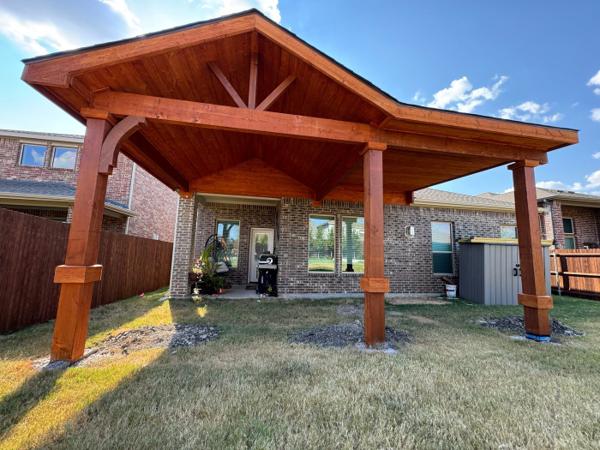 Stained wood gable covered patio with a shingled roof, knee braces and wood posts