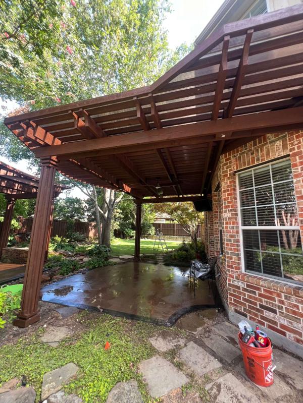 Flat-roof stained wood shade pergola attached to a brick home