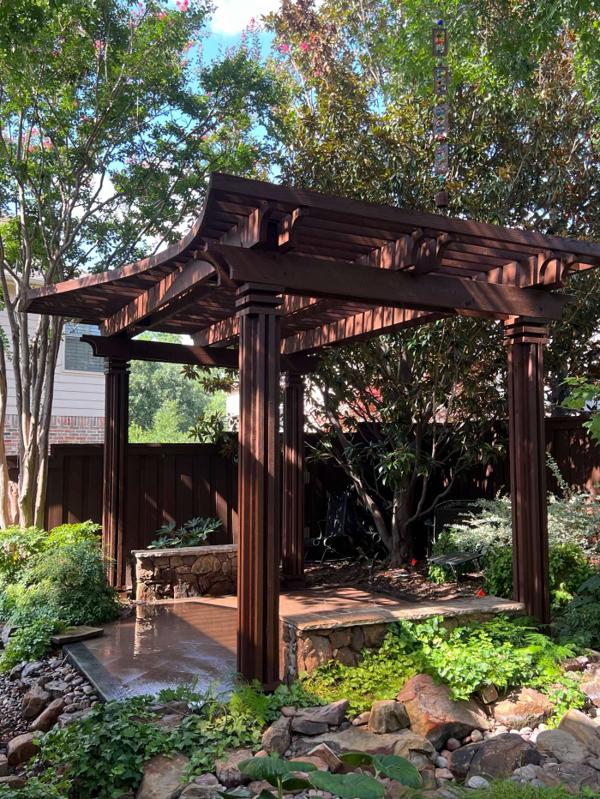 Freestanding stained wood pergola set in a landscaped garden
